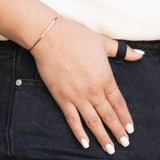 Close-up of a woman's hand wearing a Pave Diamond Ring, 4 Diamond Ring and an Off the Cuff Bracelet against dark denim. 