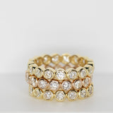 Three yellow gold The Evermore Rings against a light grey background.  