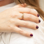 A close-up of a woman’s hand wearing two Letter Rings, G and F, and a Birthstone Ring.