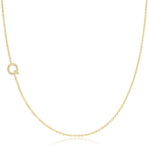 A yellow gold necklace with a pave letter Q charm on a white background. 