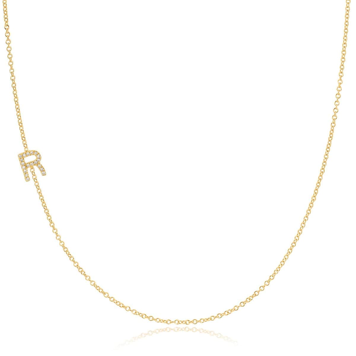 A yellow gold necklace with a pave letter R charm on a white background. 