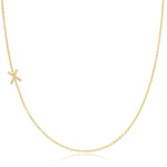 A yellow gold necklace with a pave letter X charm on a white background. 