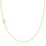 A yellow gold necklace with a pave letter E charm on a white background. 