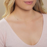 Close-up of a woman's neck wearing a yellow gold necklace with a letter J charm. 