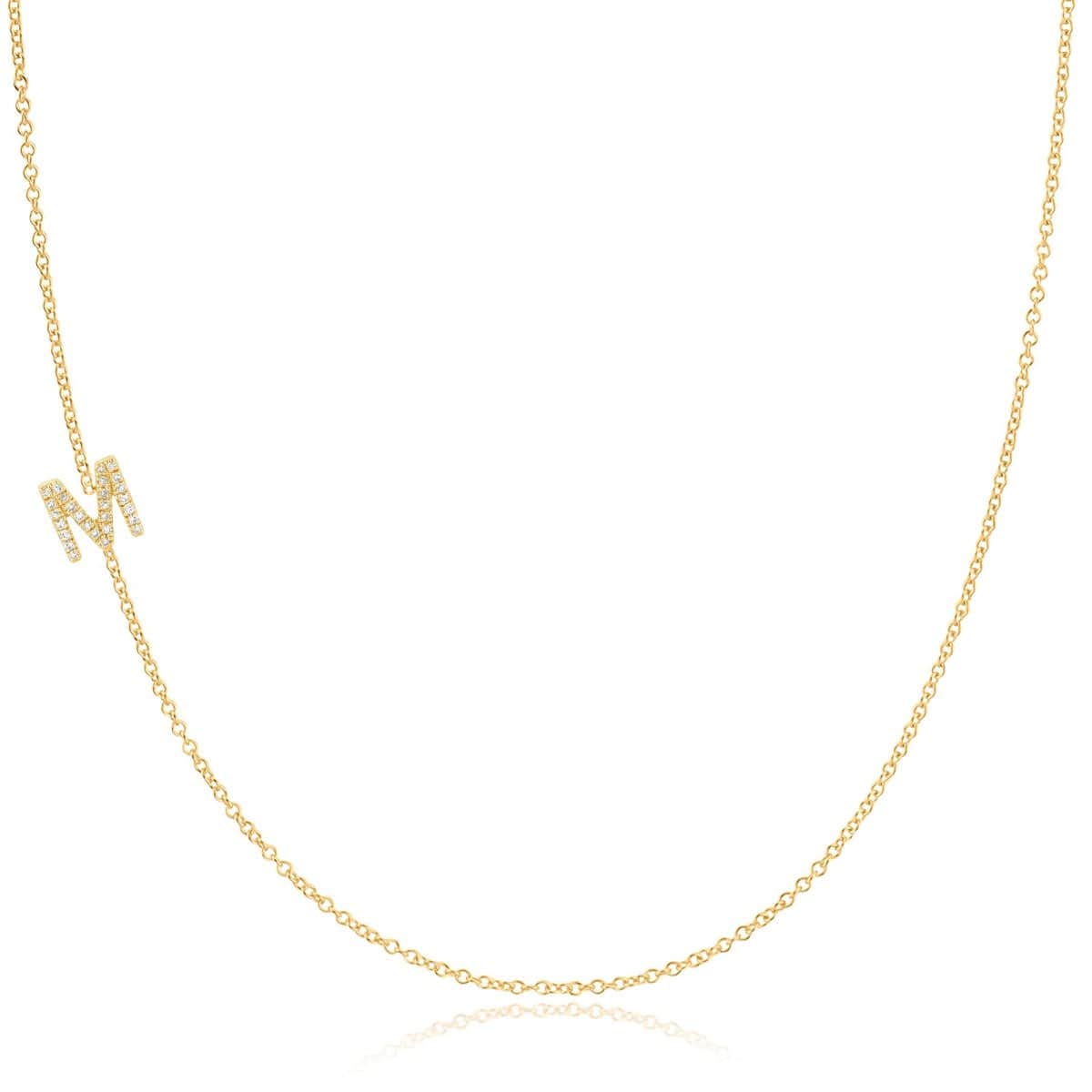 A yellow gold necklace with a pave letter M charm on a white background. 