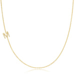 A yellow gold necklace with a pave letter M charm on a white background. 