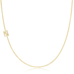 A yellow gold necklace with a pave letter N charm on a white background. 