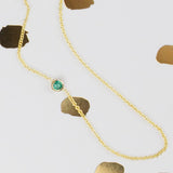 A yellow gold 14K Gold Asymmetrical Birthstone Necklace - Emerald (May) on a white background with gold round shapes. 
