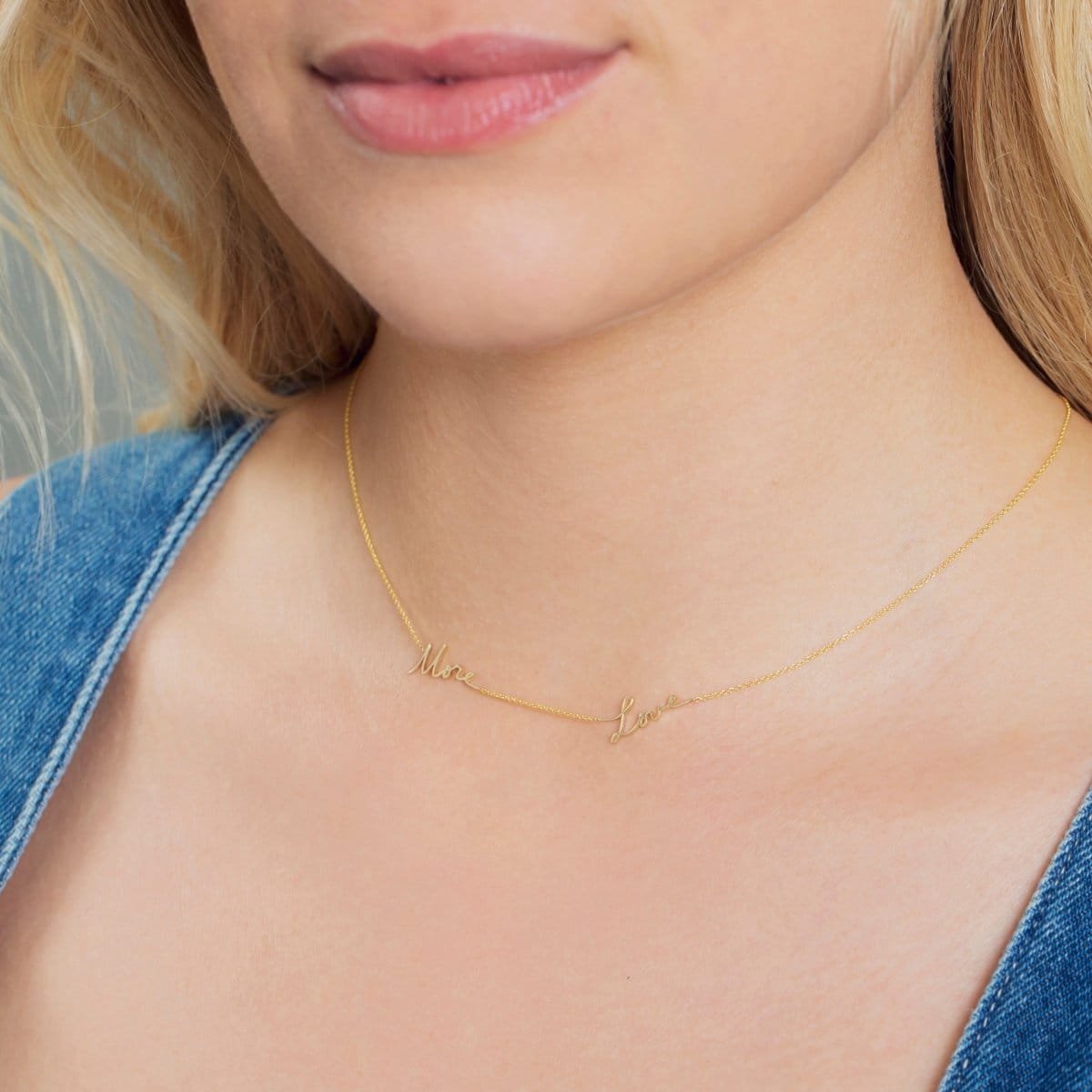 Close-up of a blonde woman's neck wearing a More Love Necklace with a blue denim top. 