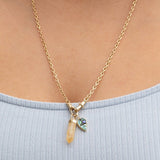 Close-up of a décolletage wearing an Oval Link Chain with an Abalone Leaf Charm and a Balance Crystal Charm with a light blue top. 