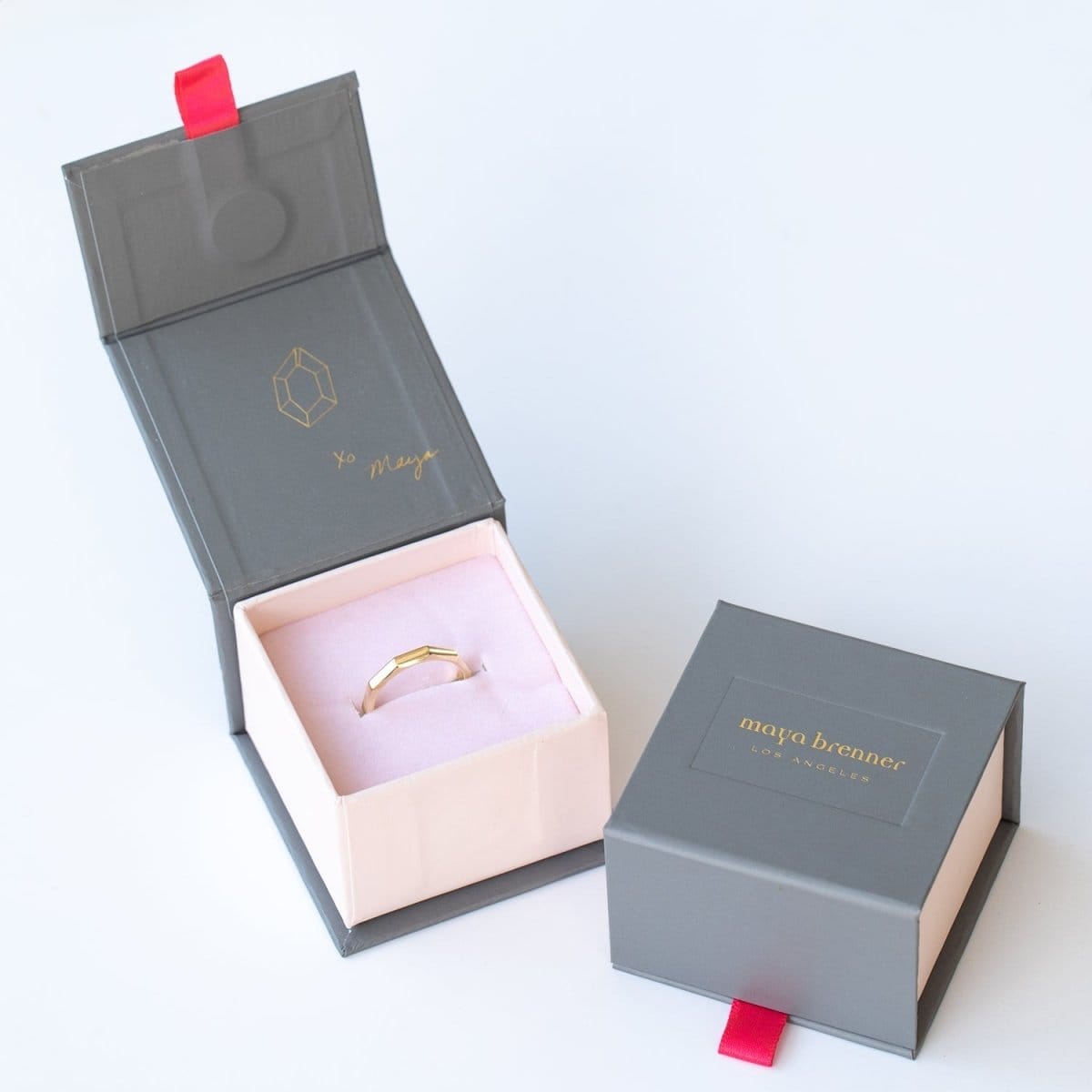 A yellow gold Tenfold Ring in a Maya Brenner jewellery box against a light grey background. 