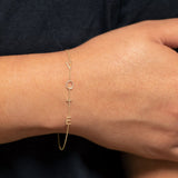 A wrist wearing a yellow gold Custom Gold Bracelet – 4 Letters  with the letters V, O, T and E, against a black background. 