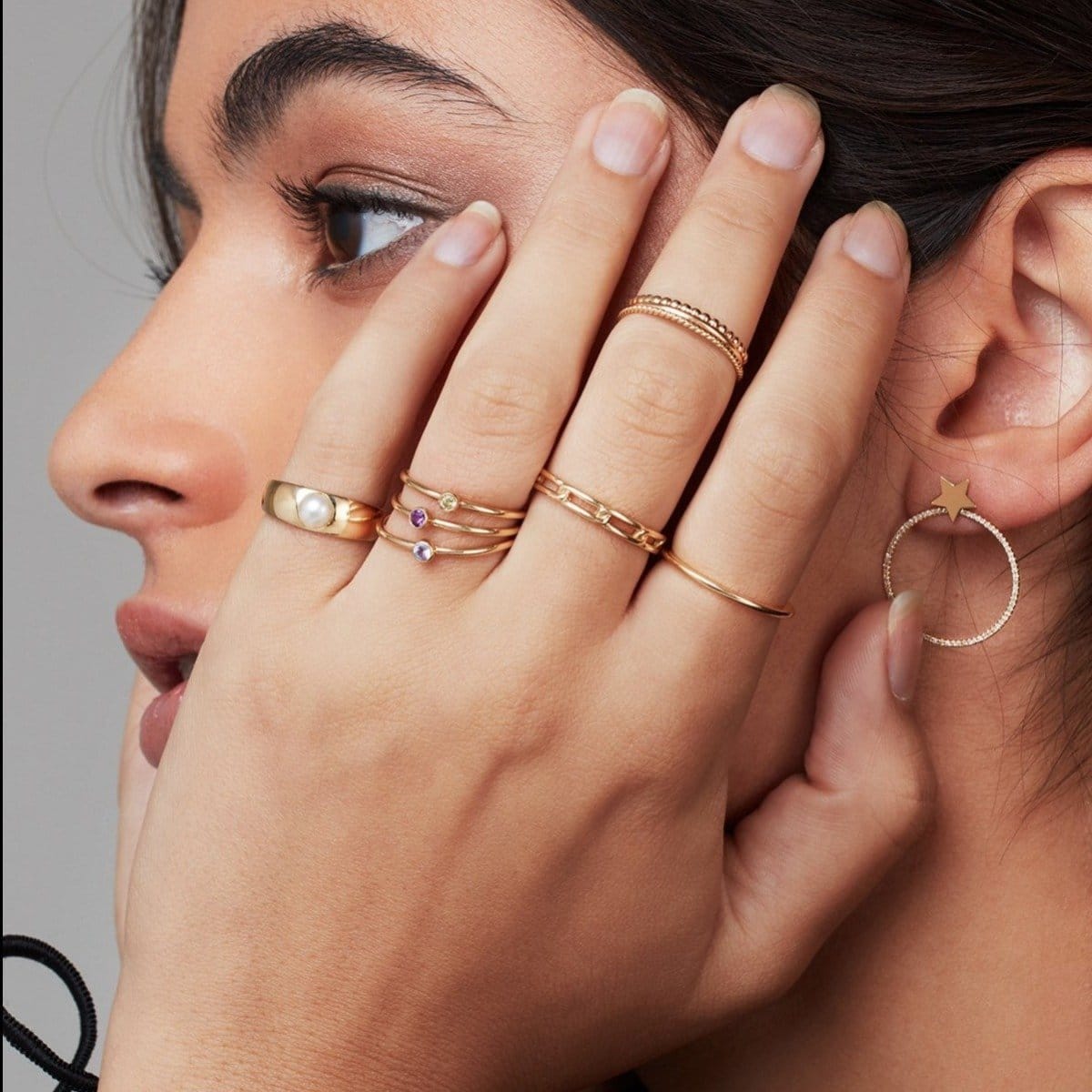 assorted gold rings worn with hands resting on woman's face