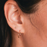 A close up of a woman's ear wearing a bithstone stud and birthstone hoop