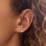 Close-up of an ear wearing a heart-shaped earring and a crescent moon earring.