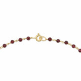 A close up of a gold clasp on a red beaded chain on a white background