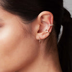 Close-up of a woman's ear wearing a Rectangle Ear Cuff, Birthstone Hoop and a Pave Double Ear Cuff. 