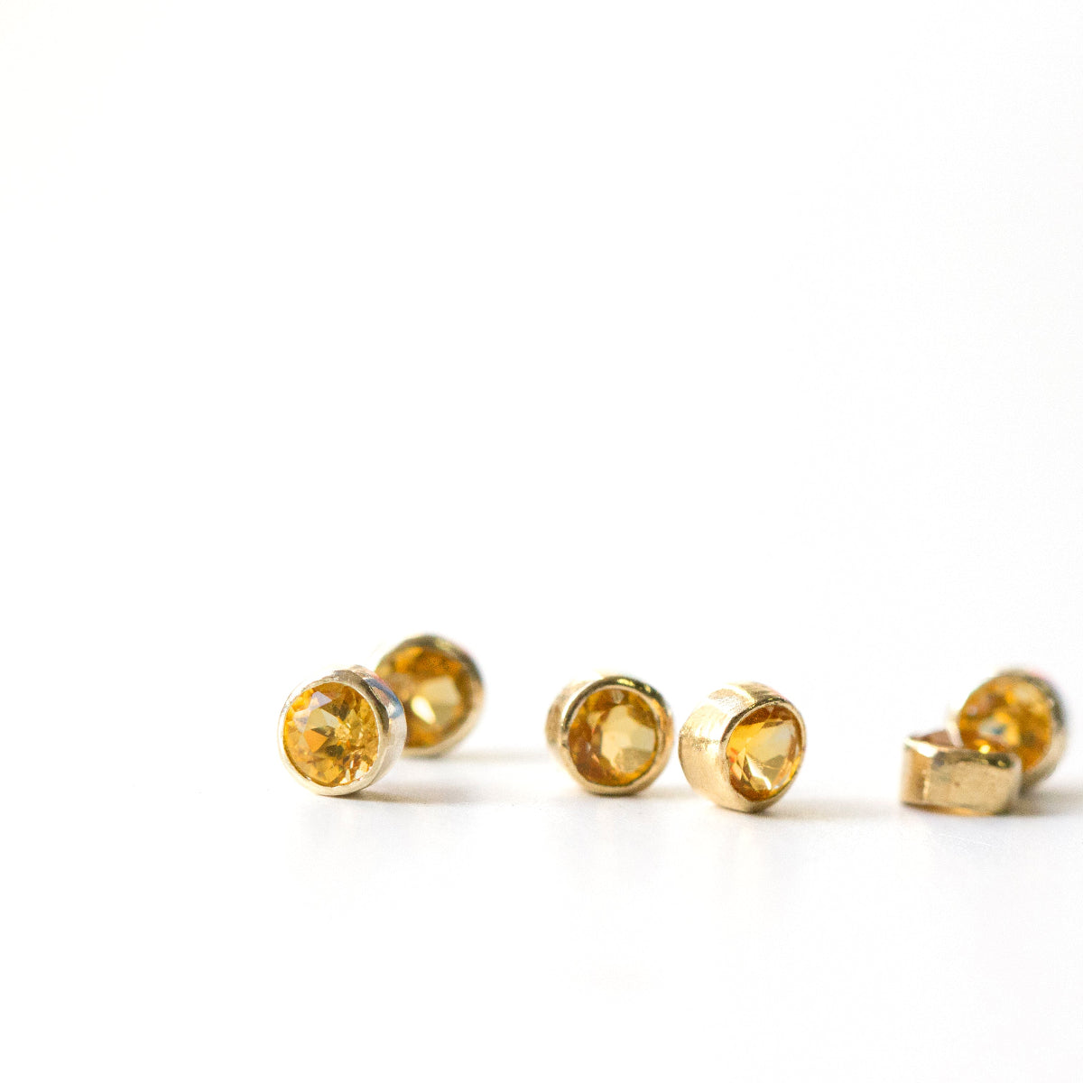 citrine bithstones in a gold bezel on a white background