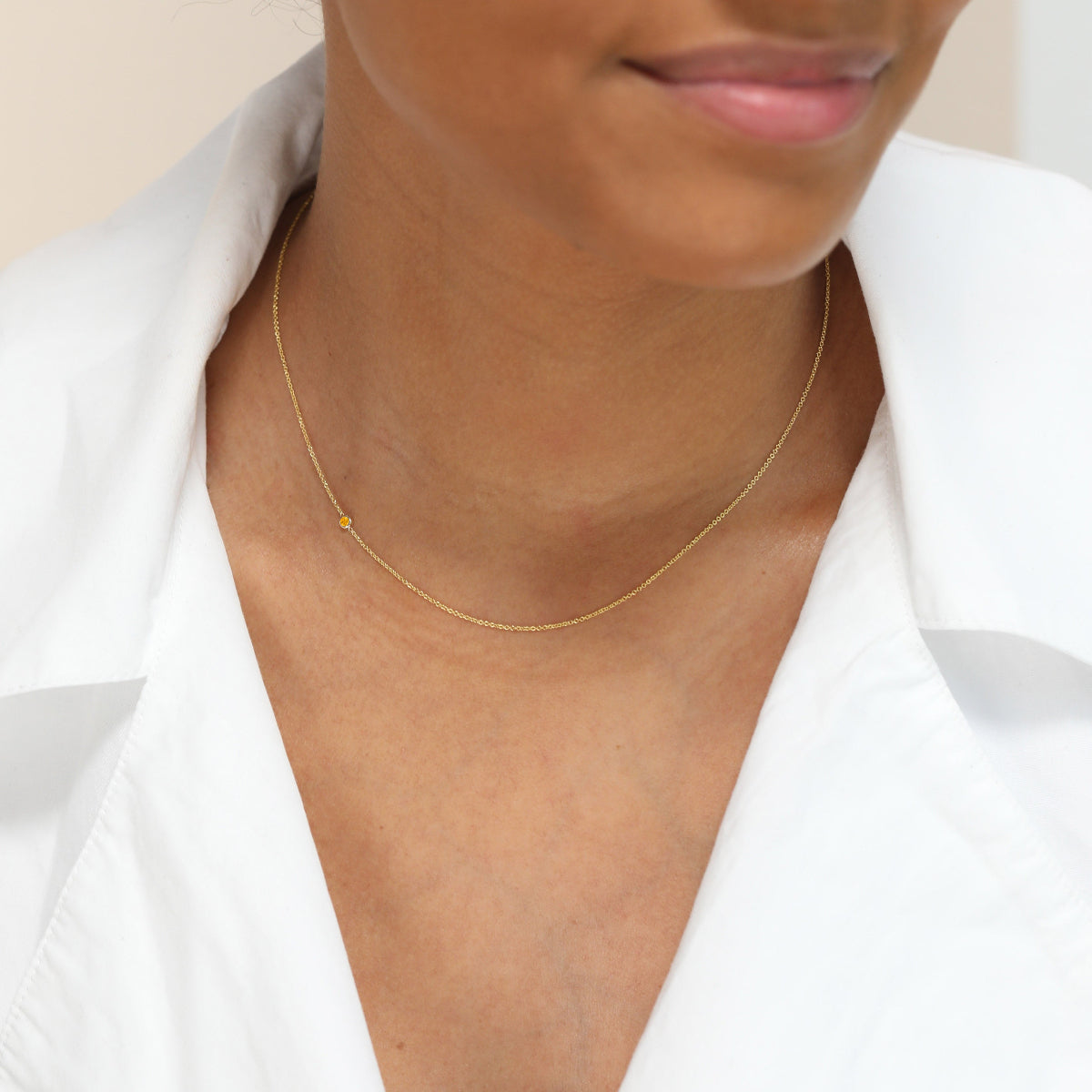 Woman wearing a citrine bitrhstone necklace and a white shirt
