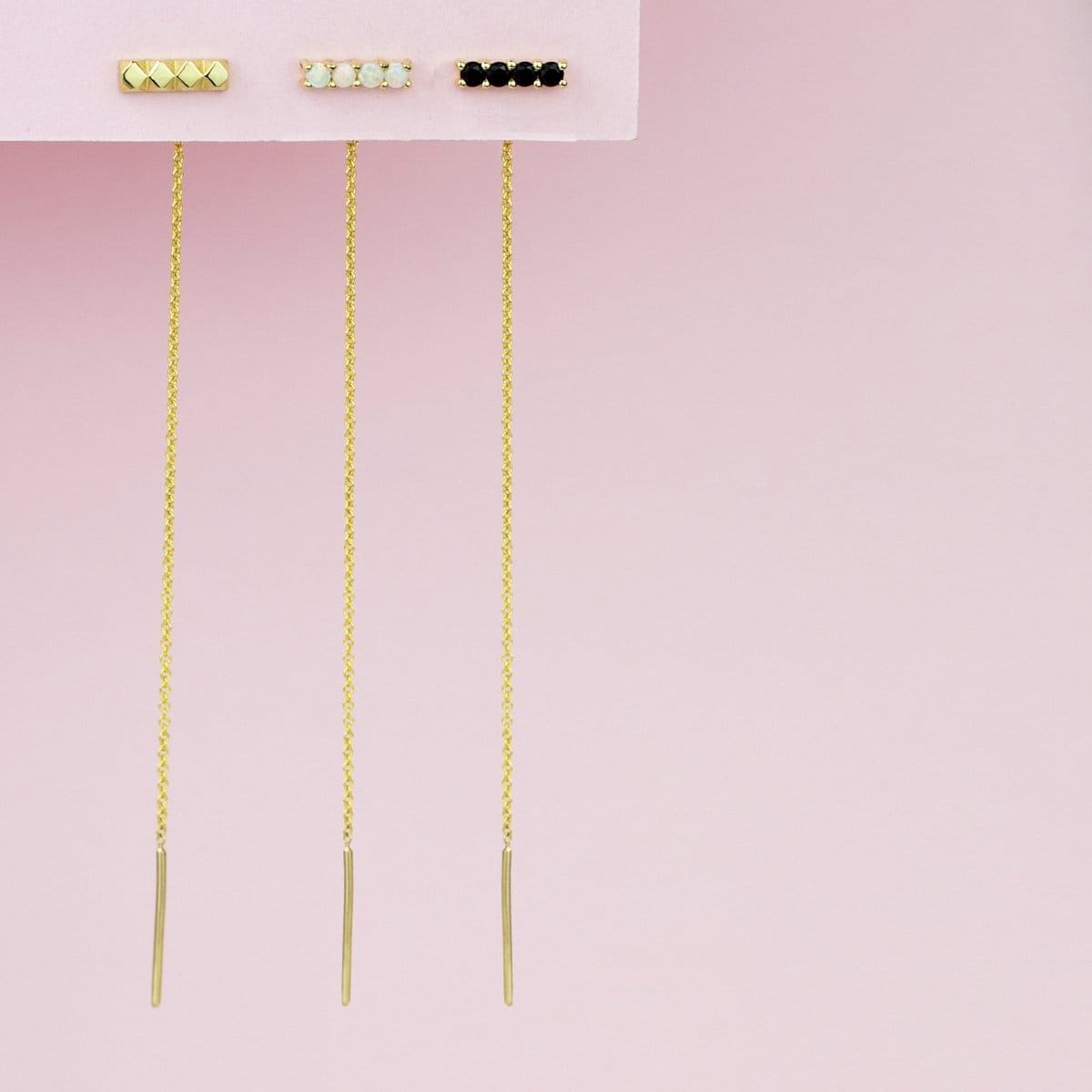 An Alli Webb Faceted Threader, Onyx Threader and Opal Threader against a light pink background. 