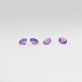 Four amethyst gemstones on a light grey background. 