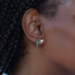 Close-up of an ear wearing an Enamel Gold Unity Earring and a Alli Webb Turquoise Huggie. 