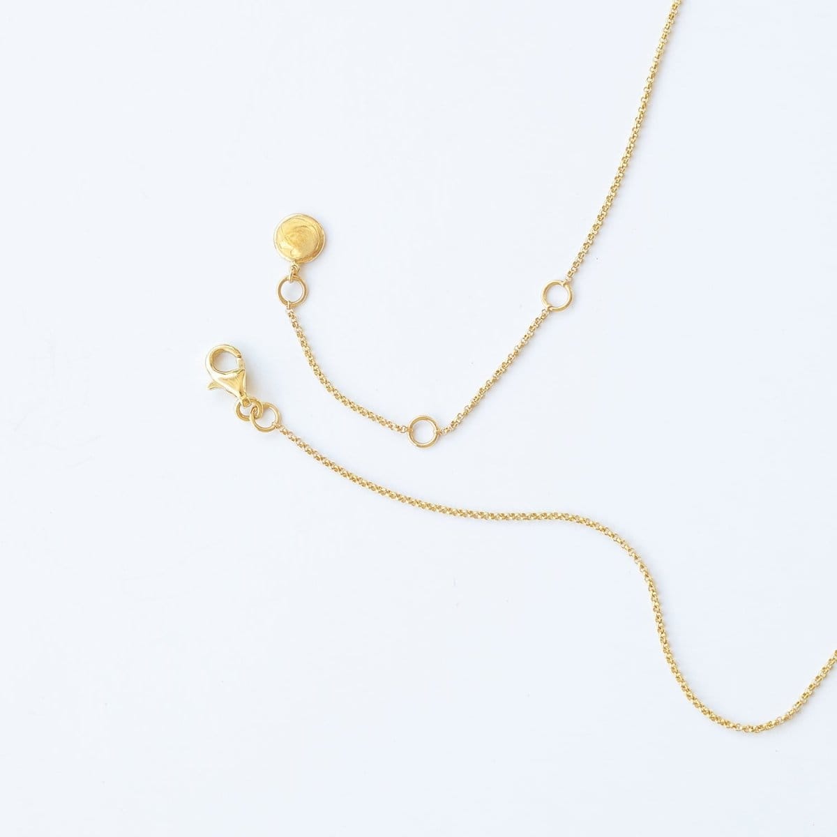 The back of a yellow gold Diamond Drip Necklace, showing a lobster clasp on a white background. 