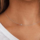 A close-up of a neck wearing two 14k Gold Asymmetrical Charm Necklaces - one heart in rose gold and one star in white gold. 