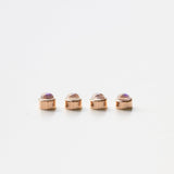 Four rose gold moonstone birthstone charms on a white background. 