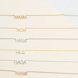 A Pavé MAMA Necklace in yellow gold, a MOM Necklace in rose gold, a Pavé NANA Necklace in white gold, a GIGI Necklace in yellow gold, a Pavé GAGA Necklace in white gold and a Pavé NANA Necklace in rose gold, against an off-white background. 
