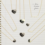 Pavé Unity Pendants - Large and Small, an Enamel Gold Unity Pendant - Small, an Enamel Gold Unity Pendant - Large, VOTE Necklace, JUSTICE Necklace and RiseUP Necklace, all in yellow gold, with a lined notepad page as the background. 