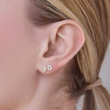 Close-up of two Pavé Charm Studs -  Star of David in white gold and Hamsa in yellow gold in a blonde woman's ear. 