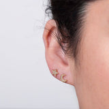 A close up of a woman's ear wearing a yellow gold pave diamond star stud and a pave diamond moon stud.
