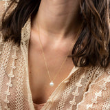 Close-up of a woman's décolletage wearing a Perla Necklace, styled in a neutral top. 