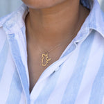 Close-up of a person's neck wearing a Quebec necklace in yellow gold with a blue and white striped shirt against a light grey blurred background.