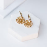 Skylight Hoops in yellow gold on a white stone surface. 