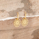 Gold Skylight Hoops on a textured beige surface.