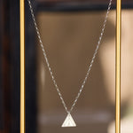 A Virtues Pendant - Triangle in sterling silver in a thin gold frame and a blurred background. 