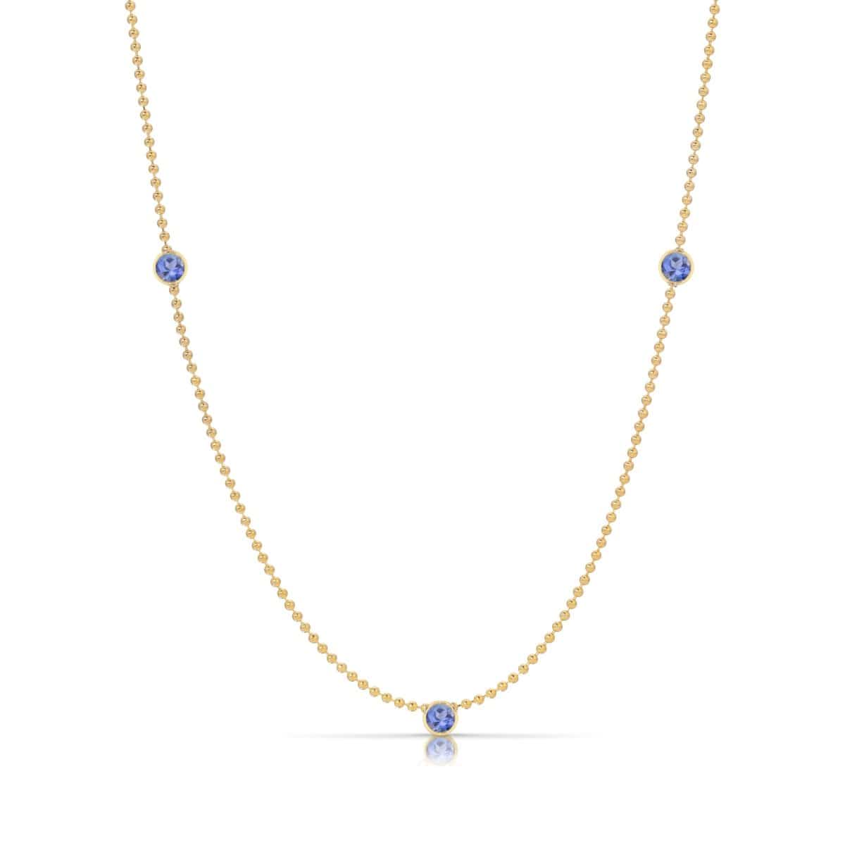 A Triple Birthstone Layering Necklace - Yellow Gold in Tanzanite - December on a white background.