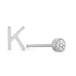 A white gold monogram earring set, featuring a mini letter K stud and a mini diamond stud on a white background. 