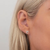 Close up of white gold crescent moon stud on a woman's ear.