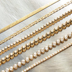 Multiple yellow gold bracelets laid against  a silver metal surface, being an Overboard Bracelet, Bubble Bracelets (Large and Small), a Love Set Match Bracelet and a Down the Line Bracelet. 