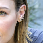 Close-up of a woman's ear wearing an Alli Webb Faceted Threader, Onyx Comfort Stud and Onyx Huggie with an outdoors blurred background. 