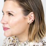 Close-up of an Alli Webb Onyx Threader, Onyx Huggie and Onyx Comfort Stud worn by a woman with short blonde hair and a printed top against a light grey background. 