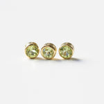 Three yellow gold peridot birthstone charms on a white background. 
