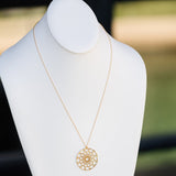 A Skylight Necklace in yellow gold on a white mannequin against a blurred background. 